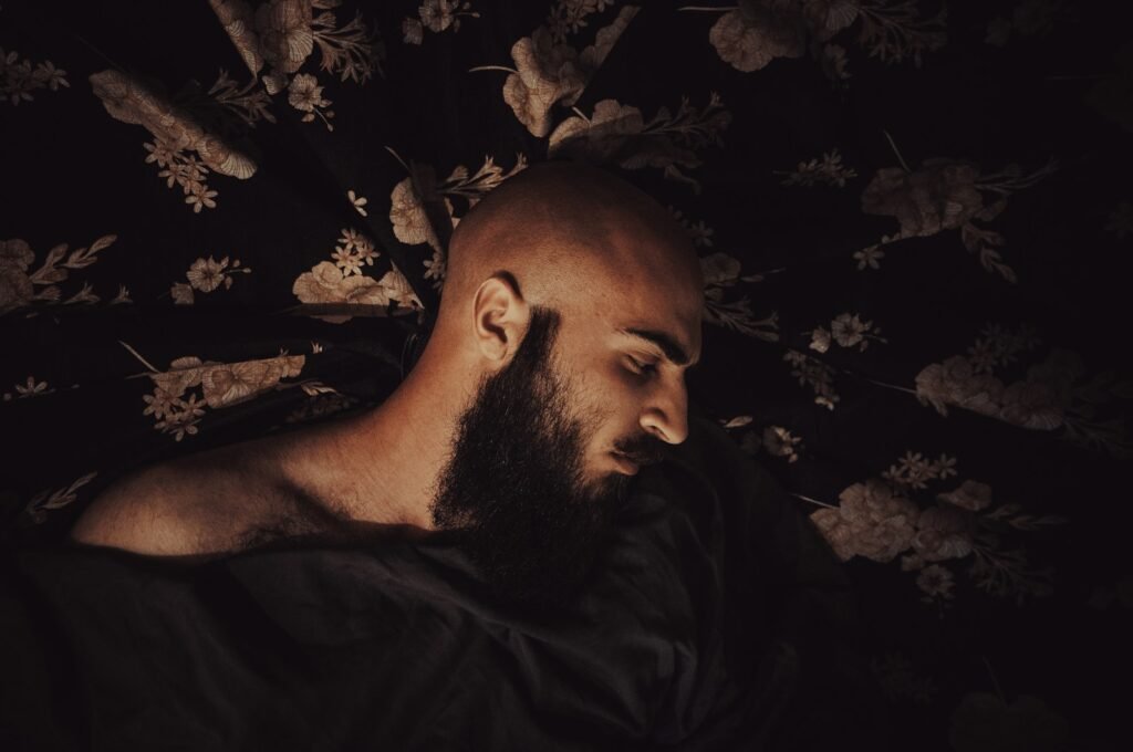 A man with a beard laying down in the dark