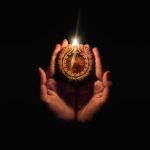 A person holding a lit candle in their hands