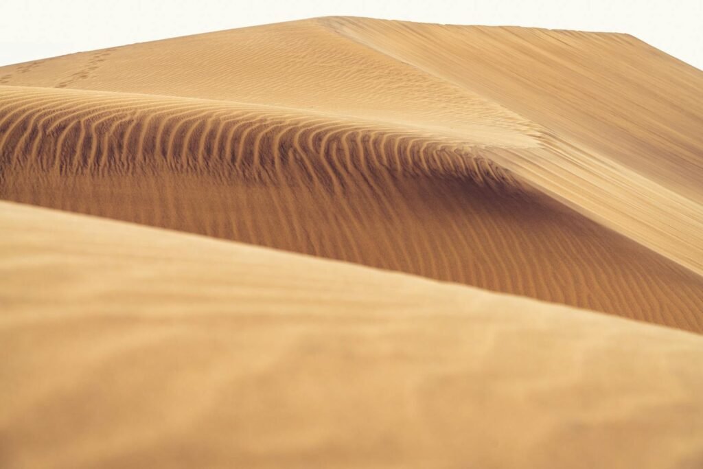 Golden sand dunes captured in sunlight, showcasing nature's mesmerizing patterns.