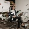Businesswoman in modern office with falling cash, symbolizing financial success.