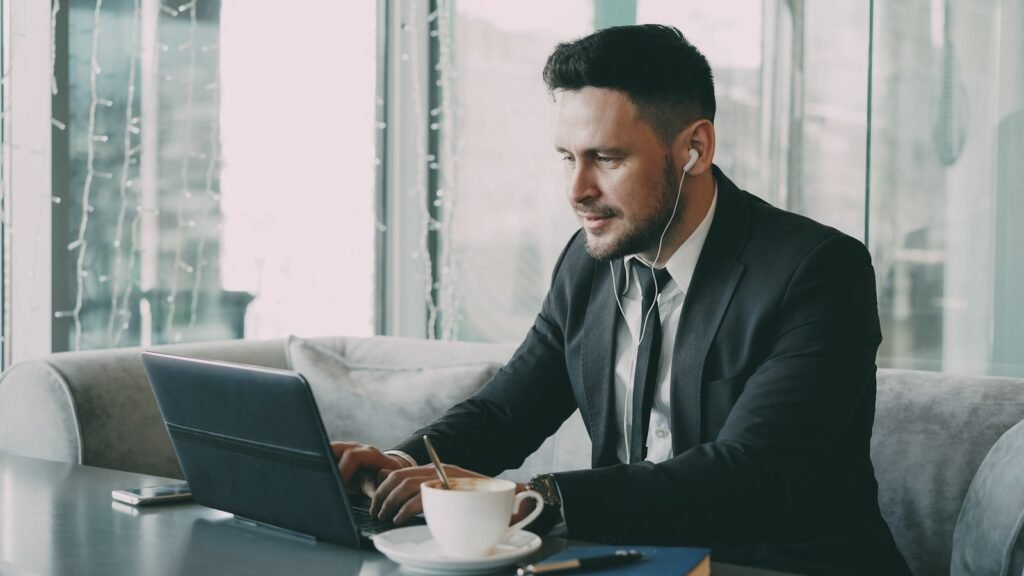 Man in suit working on laptop with coffee.