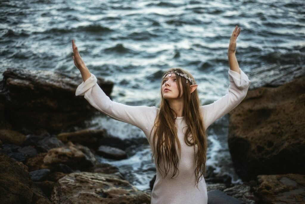 A woman with her hands up in the air by a body of water